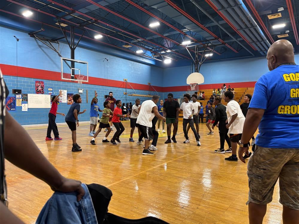  students and staff on the basketball court playing.